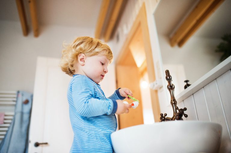cute toddler boy brushing his teeth in the bathroom .jpg