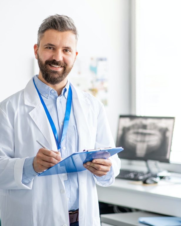 mature dentist in modern dental surgery looking at camera.jpg